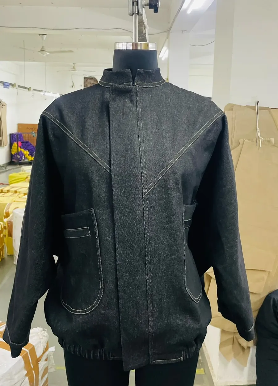 Black denim jacket with stand collar, V-yoke topstitching and patch pockets on a dress form